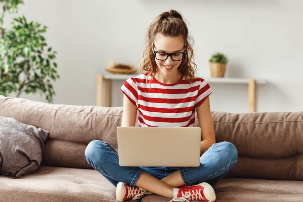 Joyful relaxed woman using laptop with interest at home